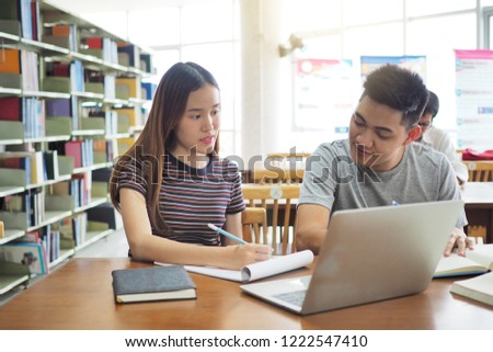 Two students reading together in the library.        