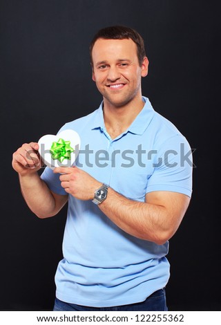 Handsome man smiling and holding a gift over a black background