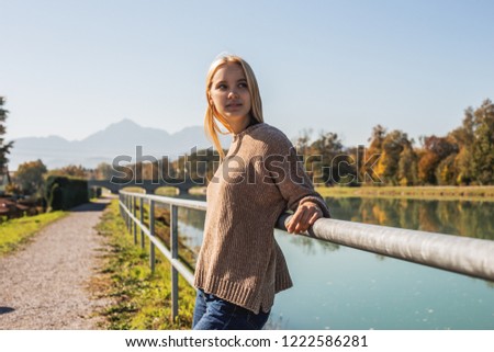 Young woman traveler walks along the embankment near a mountain river, looks into the distance and dreams. A trip to the mountains, a tour abroad, a trip to the mountain. Picture for advertising