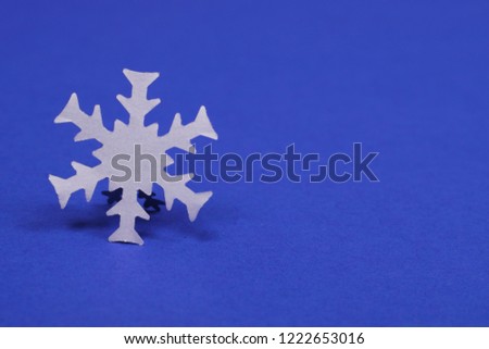 Big white paper snowflake on dark blue background with copy space. Winter concept.