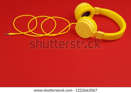 Yellow headphones on red background. Music concept.
