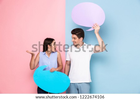 Image of excited man and woman holding copyspace posters for announcement isolated over colorful background