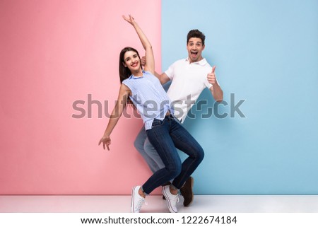 Full length image of optimistic man and woman in casual wear laughing and having fun together isolated over colorful background