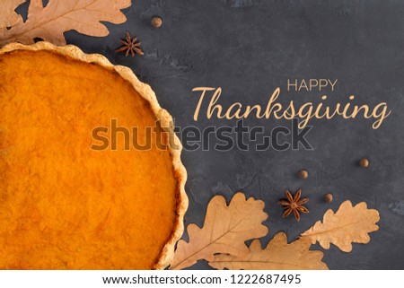 Frame from orange pumpkin pie, spices, autumn leaves on concrete dark gray background with text, toned. Happy Thanksgiving Day, culinary, recipe, menu concept. Top view, flat lay, copy space, mock up