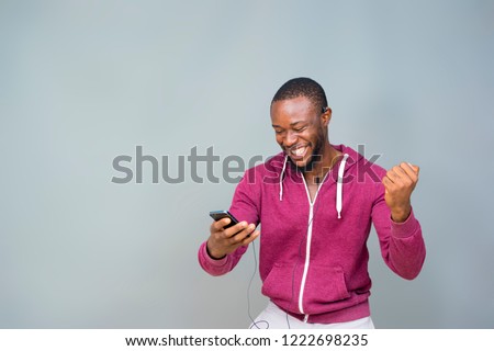 young black man happy and excited and celebrating while looking at his mobile phone  Royalty-Free Stock Photo #1222698235
