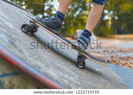 A child skates on a longboard at a ramp, close-up