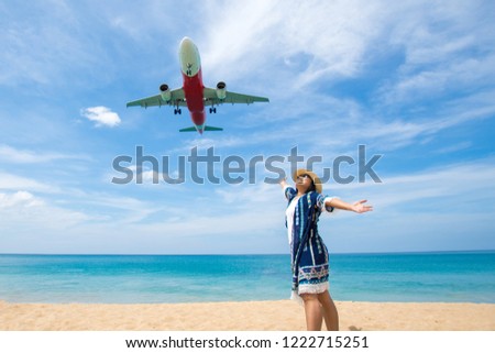 woman stand at the sea Mai khao beach Phuket Province, Thailand take photo with airplane landing. soft focus.