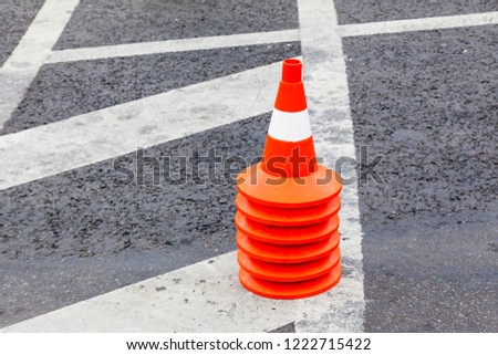 Road cones collected in a stack on asphalt with a marking