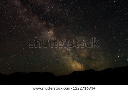 Outer space with many stars, meteors and the Milky Way galaxy over the mountains