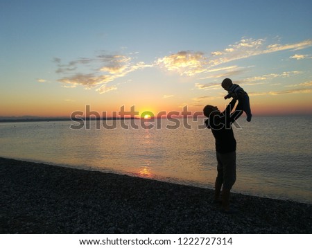 Father holding his baby up during sunrise