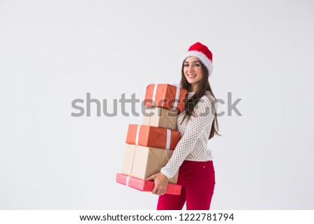 Christmas and holidays concept - woman in santa hat with many gifts on white background with copy space