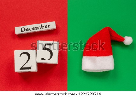 Wooden calendar December 25th and Santa hat on red and green background. Top view Flat lay Concept