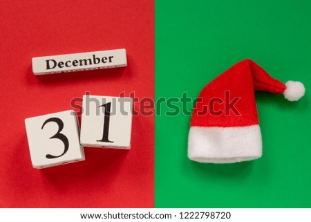 Wooden calendar December 31st and Santa or Father Frost hat on red and green background. Top view Flat lay Concept
