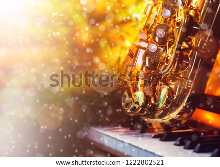 close up of saxophone on piano keys with blurred Christmas tree and snowfall , Christmas background with copy space