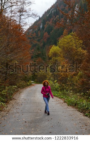 Woman tourist with camera walking on a mountain road