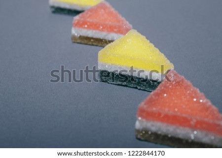 Colorful triangular jelly candy on gray background.