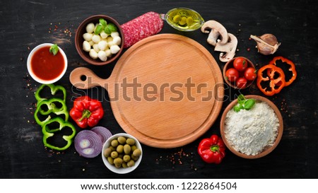 Ingredients for pizza. Mushrooms, sausages, tomatoes, vegetables. Top view. On a black wooden background. Free copy space.