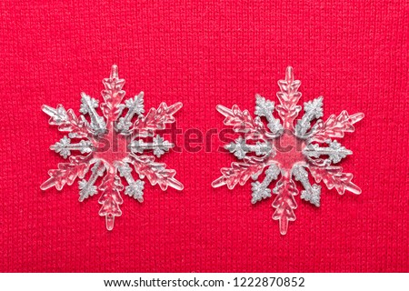 Christmas snowflakes on red knit background. Top view with copy space.