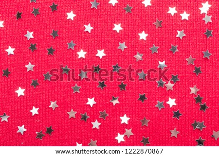 Silver star glitter on red knit background. Top view with copy space.