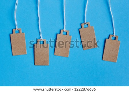 Blank brown cardboard price tags, sale tag, gift tag, address label, luggage label on blue background. Mock up, copy space for text, top view