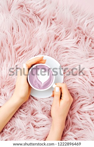 Female hands holding a cup of coffee on the fluffy fur plaid.  Flat lay, top view