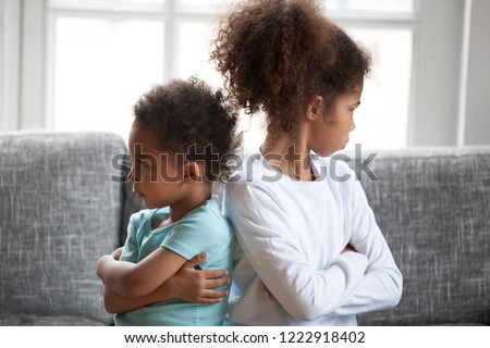 Offended African American siblings sitting ignoring, turning away from each other with arms crossed, bad relationships between little preschooler sister and toddler brother, children conflict Royalty-Free Stock Photo #1222918402