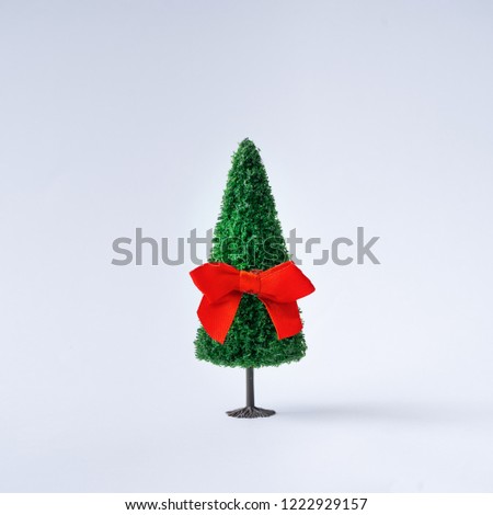 Christmas tree with red satin gift bow on red background. Minimal New Year concept.