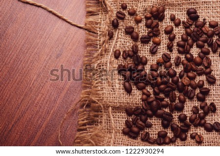 Cafe design, pictures for bars and cafes. Closeup coffee grains on burlap and brown background.