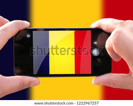 The concept of tourism and travel. The hands of men make a telephone photograph of the flag of Chad. On the smartphone close-up image of the flag. Photos for social networks, blogs, instagram.