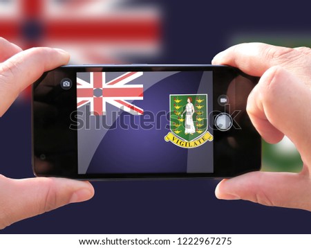 The concept of tourism and travel. The hands of men make a telephone photograph of the flag of British Virgin Islands. On the smartphone close-up image of the flag. Photos for social networks, blogs