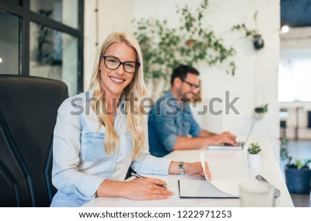 Business portrait of a gorgeous blonde woman. Coworker in the background.