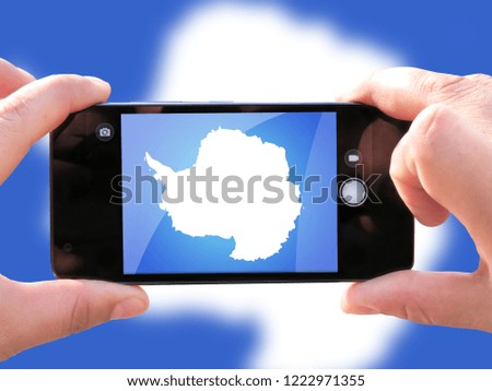 The concept of tourism and travel. The hands of men make a telephone photograph of the flag of Antarctic. On the smartphone close-up image of the flag. Photos for social networks, blogs, instagram.
