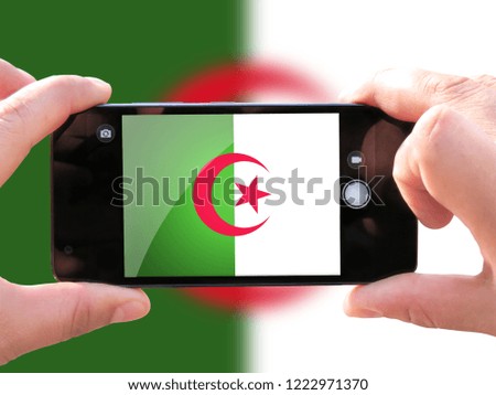 The concept of tourism and travel. The hands of men make a telephone photograph of the flag of Algeria. On the smartphone close-up image of the flag. Photos for social networks, blogs, instagram.