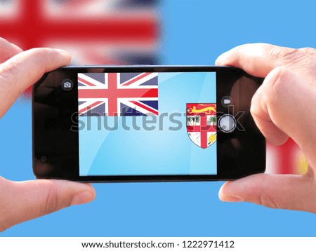 The concept of tourism and travel. The hands of men make a telephone photograph of the flag of Fiji. On the smartphone close-up image of the flag. Photos for social networks, blogs, instagram.