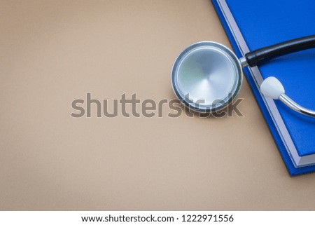 stethoscope and a book on brown background
