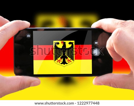 The concept of tourism and travel. The hands of men make a telephone photograph of the flag of Germany. On the smartphone close-up image of the flag. Photos for social networks, blogs, instagram.