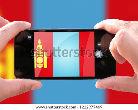 The concept of tourism and travel. The hands of men make a telephone photograph of the flag of Mongolia. On the smartphone close-up image of the flag. Photos for social networks, blogs, instagram.