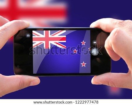 The concept of tourism and travel. The hands of men make a telephone photograph of the flag of New Zealand. On the smartphone close-up image of the flag. Photos for social networks, blogs, instagram.