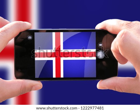 The concept of tourism and travel. The hands of men make a telephone photograph of the flag of Iceland. On the smartphone close-up image of the flag. Photos for social networks, blogs, instagram.