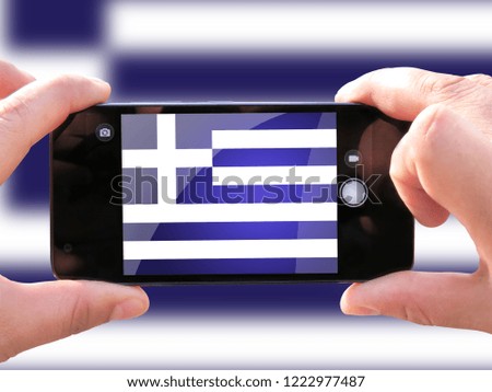 The concept of tourism and travel. The hands of men make a telephone photograph of the flag of Greece. On the smartphone close-up image of the flag. Photos for social networks, blogs, instagram.