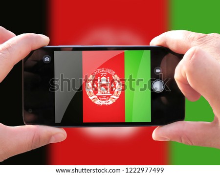 The concept of tourism and travel. The hands of men make a telephone photograph of the flag of Afghanistan. On the smartphone close-up image of the flag. Photos for social networks, blogs, instagram.