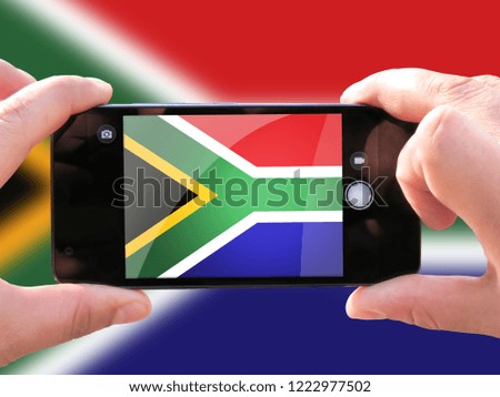 The concept of tourism and travel. The hands of men make a telephone photograph of the flag of South Africa. On the smartphone close-up image of the flag. Photos for social networks, blogs, instagram.