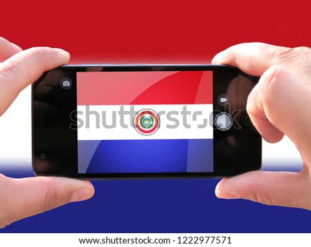 The concept of tourism and travel. The hands of men make a telephone photograph of the flag of Paraguay. On the smartphone close-up image of the flag. Photos for social networks, blogs, instagram.
