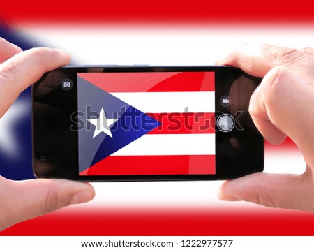 The concept of tourism and travel. The hands of men make a telephone photograph of the flag of Puerto Rico. On the smartphone close-up image of the flag. Photos for social networks, blogs, instagram.