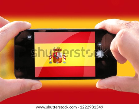 The concept of tourism and travel. The hands of men make a telephone photograph of the flag of Spain. On the smartphone close-up image of the flag. Photos for social networks, blogs, instagram.