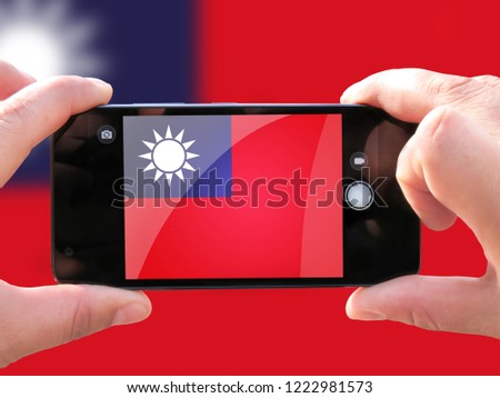 The concept of tourism and travel. The hands of men make a telephone photograph of the flag of Taiwan. On the smartphone close-up image of the flag. Photos for social networks, blogs, instagram.
