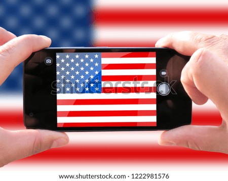 The concept of tourism and travel. The hands of men make a telephone photograph of the flag of USA. On the smartphone close-up image of the flag. Photos for social networks, blogs, instagram.