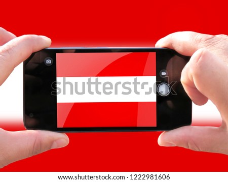 The concept of tourism and travel. The hands of men make a telephone photograph of the flag of Austria. On the smartphone close-up image of the flag. Photos for social networks, blogs, instagram.