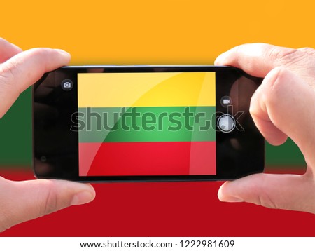 The concept of tourism and travel. The hands of men make a telephone photograph of the flag of Lithuania. On the smartphone close-up image of the flag. Photos for social networks, blogs, instagram.