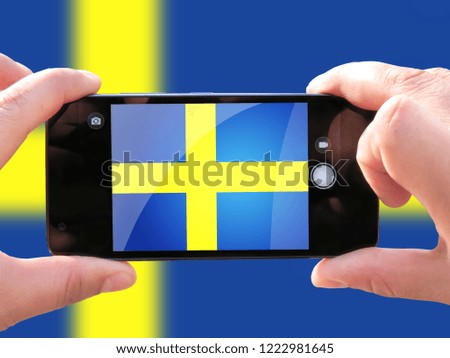 The concept of tourism and travel. The hands of men make a telephone photograph of the flag of Sweden. On the smartphone close-up image of the flag. Photos for social networks, blogs, instagram.